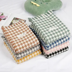 Detailed view of colorful houndstooth cashmere-feel scarves stacked neatly with cute props.