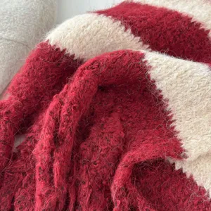 Close-up detail of the soft fuzzy red and white striped knit scarf texture, cozy winter accessory.