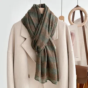 Detailopname van een geplooide groene damessjaal met gouden strepen voor de herfst.