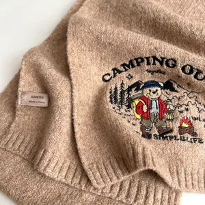 Detailed view of the cozy winter knit scarf featuring cute bear embroidery and soft fabric.