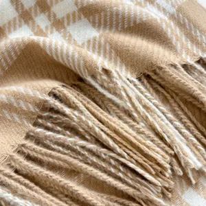 Detailed close-up view of a cozy autumn and winter plaid fringed scarf in beige and white.