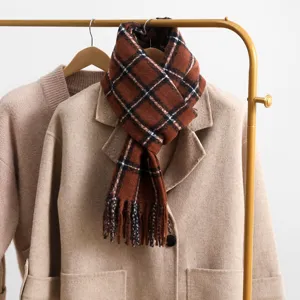 Detailed view of the retro brown plaid winter scarf draped on a coat, warm and cozy style.