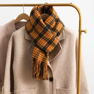 Plaid winter scarf detail showing cozy yellow and green checkered texture with stylish fringe.