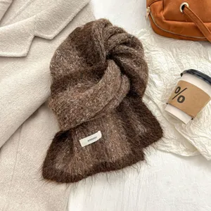 Close-up detail of cozy brown mohair-blend knit scarf showcasing soft plush texture and woven label.
