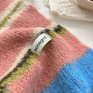 Detailed view of women wool loop yarn colorblock striped scarf, soft knit texture.