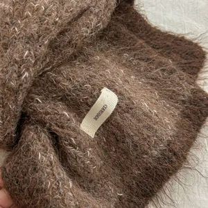 Detailed shot of cozy fuzzy brown mohair knit winter scarf texture with brand label.