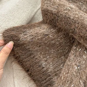 Close-up detail of soft brown mohair knit scarf texture showing cozy winter material.