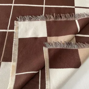 Primo piano dettagliato della morbida sciarpa a quadri marrone e beige con frange.