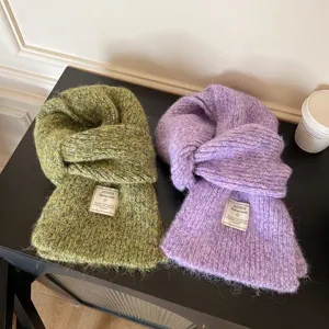 Close-up detail of cozy soft knitted wool winter scarves in green and purple colors, warm neck.