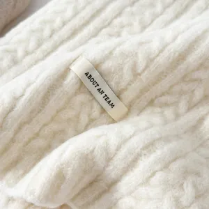 Detailed close-up of a cozy cream white cable knit winter scarf, soft wool blend texture.