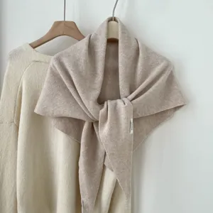 Detailopname van gezellige gebreide wollen driehoekssjaal in haverkleur, elegante drapering.