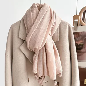 Detailed view of a light pink linen cotton scarf with cute fringe tassels and wooden beads.