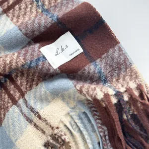 Close-up detail view of cozy winter plaid scarf with fringe, soft cashmere-feel texture.