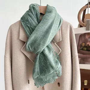 Green lace trim scarf detail showing soft texture and elegant embroidered edge design.
