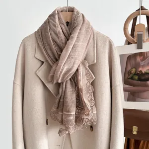 Detailed view of the elegant beige scarf with exquisite lace trim, perfect for autumn styling.