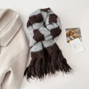 Close-up detail of the cozy fuzzy knitted striped fringe scarf in brown and grey checks.