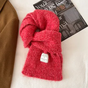 Red knit scarf detail shot, showing soft wool texture and brand label design for winter cold.