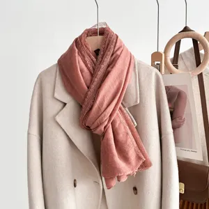 Detail view of a pink lace edge scarf draped on a beige coat, soft and elegant style.