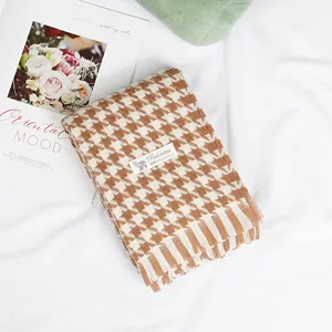 Detailed shot of brown and white houndstooth scarf with soft fringe and warm cashmere feel.