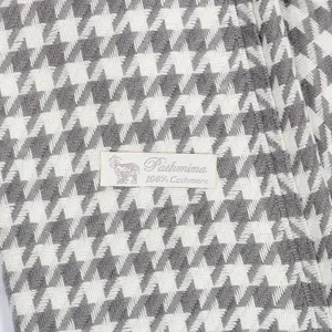 Close-up detail of classic houndstooth cashmere scarf with soft woven texture.