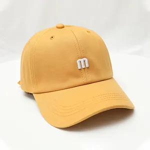 Close-up detail of a vibrant yellow baseball cap featuring trendy white 3D letter embroidery.