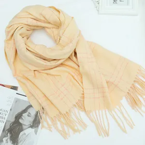 Detailed view of yellow plaid winter scarf with soft texture and delicate fringe trim.