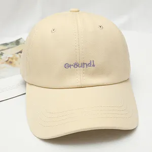 Beige cotton baseball cap detail shot featuring purple embroidered lettering on the front.