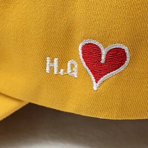 Detailopname van gele honkbalpet met rood hart en wit geborduurd detail voor dagelijks