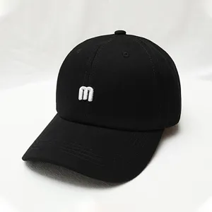 Close up view of black baseball cap featuring white 3d embroidered letter m detail.