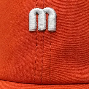 Orange baseball cap close-up featuring white 3d letter embroidery and fine stitching details.