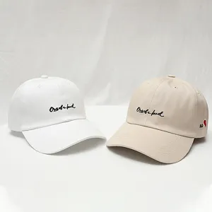 Unisex koppel honkbalpet met gebogen brim en stijlvol borduurwerk. Wit en beige.