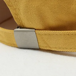 Close-up view of the adjustable metal buckle and yellow fabric strap on a baseball cap.
