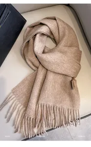 Close-up detail of the cozy beige wool scarf featuring soft tassels and fine texture.