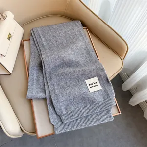 Sciarpa in lana lavorata a maglia grigia per donna, accessorio invernale caldo e spesso ben presentato.