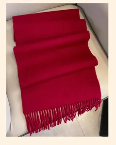 Detailed shot of a solid red winter wool scarf, beautifully folded with fringe hem, warm.