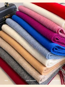 Detail shot of thick wool scarves in assorted vibrant colors stacked neatly for winter warmth.