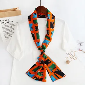 Detailed shot of an orange skinny silk twilly scarf with colorful abstract animal print design.