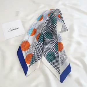 Detailed close-up of a stylish silk square scarf with geometric and paisley print patterns.