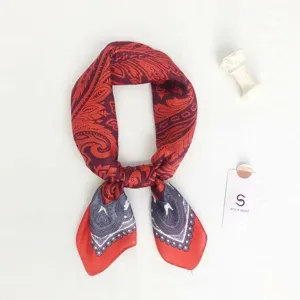 Detailed shot of a stylish paisley print silk scarf with vibrant red and purple tones.