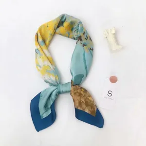 Detail view of a stylish abstract art silk scarf in blue and yellow tones, elegant accessory.