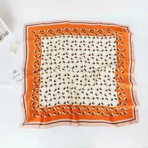 Detail view of the orange floral printed silk square scarf, perfect for neck or hair styling.