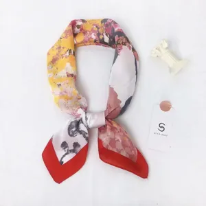 Detailed view of a fashionable floral silk square scarf with a striking red border design.