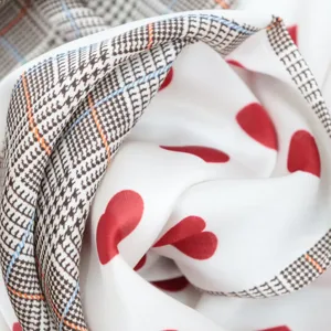 Vue detaillee d'un foulard en soie tendance avec bordure pied-de-poule et motif coeur.