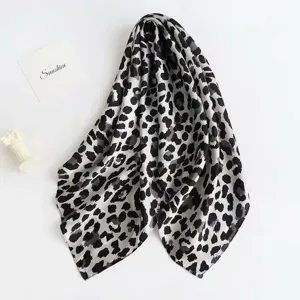 Detail shot of a chic black and white leopard print silk-feel square scarf for women.