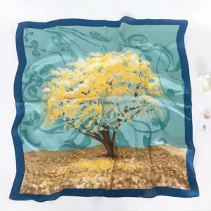 Detail view of a square silk scarf with a blue border and yellow tree art print.