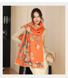 Detailed view of the elegant orange floral cashmere-like scarf worn by model in winter style scene.