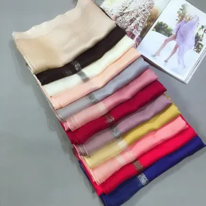 Detailed shot of multi-color long silk cotton scarves with glittering gold edge trim.