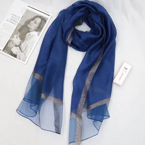 Elegant blue sheer scarf with shimmering gold trim, lightweight stylish fashion wrap.
