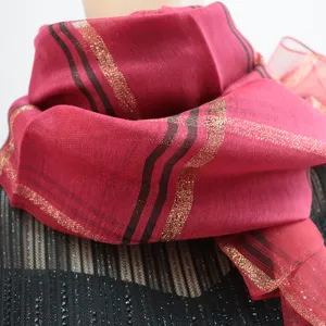 Detail view of red silk scarf featuring elegant black and gold metallic stripes.