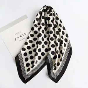 Close-up detail of black and white polka dot square scarf with elegant striped border design.